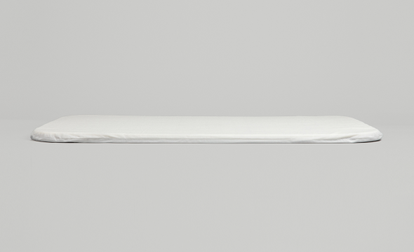 Full side profile of the white Cradlewise crib mattress, displaying its slim construction and rounded edges against a light gray background.
