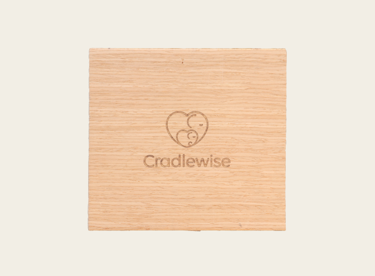 Cradlewise wood swatch featuring a natural white oak veneer finish with the Cradlewise logo engraved in the center.