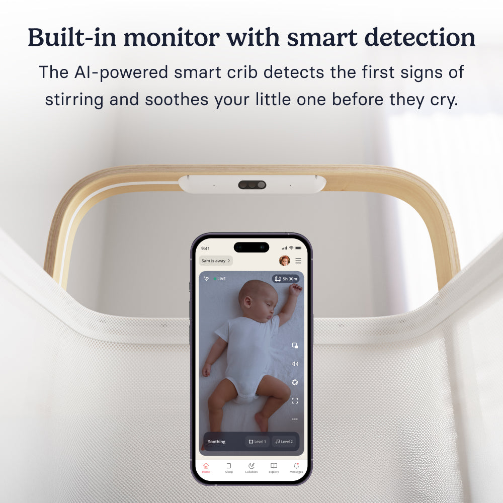 Close-up of the Cradlewise crib’s built-in camera above a phone displaying live video of a sleeping baby through the baby monitor.