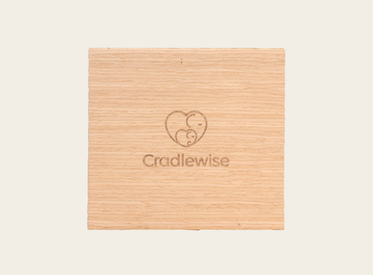 Cradlewise wood swatch featuring a natural white oak veneer finish with the Cradlewise logo engraved in the center.