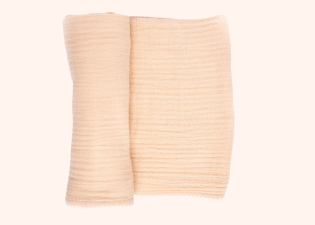 Peach Cradlewise Muslin Blanket partially rolled to show its lightweight construction and naturally crinkled muslin weave.